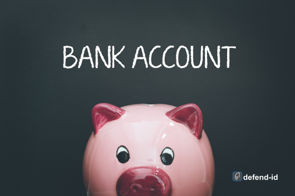Pink piggy bank on a dark background with 'BANK ACCOUNT' written in white chalk above, featuring a watermark for 'defend-id'